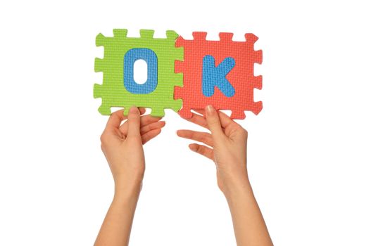 teacher holding in the hand the amusing colored educational puzzles with the word ok