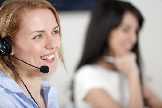 Two colleagues working in a busy call centre office.