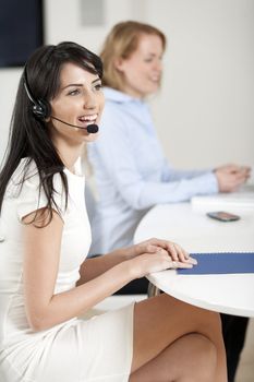 Two colleagues working in a busy call centre office.