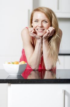 Young woman wearing pink knighty in kitchen eating breakfast