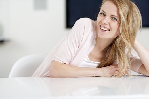 Young woman in pink shirt sitting at dining table at home