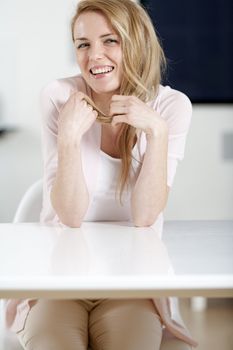 Young woman in pink shirt sitting at dining table at home