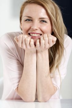 Young woman in pink shirt sitting at dining table at home