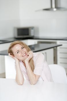 Young woman in pink shirt sitting at dining table at home