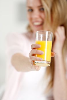 Young woman holding up a glass of orange juice.