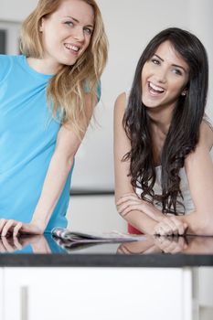 Two young woman chatting and sharing a magazine