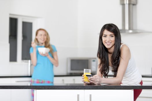 Two young woman having juice and breakfast at home