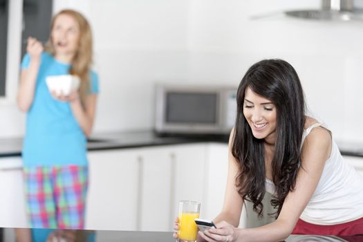 Two young woman having juice and breakfast at home