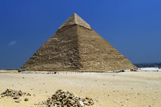 A row of camels transport tourists in front of all of the Giza Pyramids in Cairo, Egypt