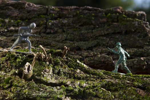 a grey and green plastic toy soldier in the middle of a battle on top of wood