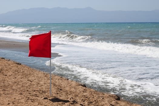 Red flag on the beach, caution of heavy waves, no swimming
