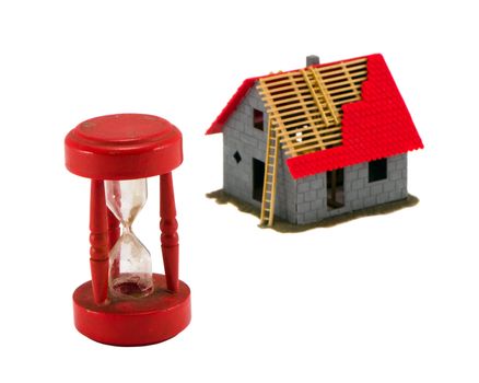 Broken sand glass and unfinished building model figure isolated on white. Construction industry bubble blow concept.