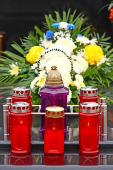 Illuminated votive candles glows on a grave, lantern