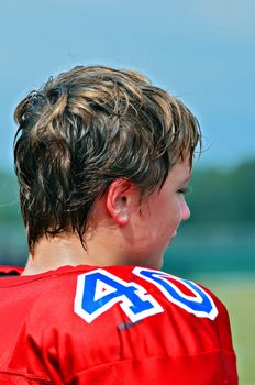 Preteen football player watching action on the field.