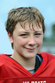 A preteen football player smiling during a break in the game.