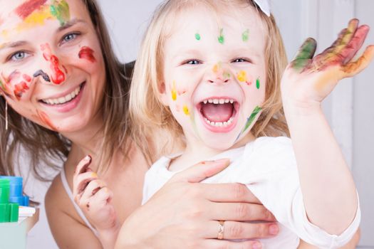 Happy mother and daughter with paint on faces, focus on baby