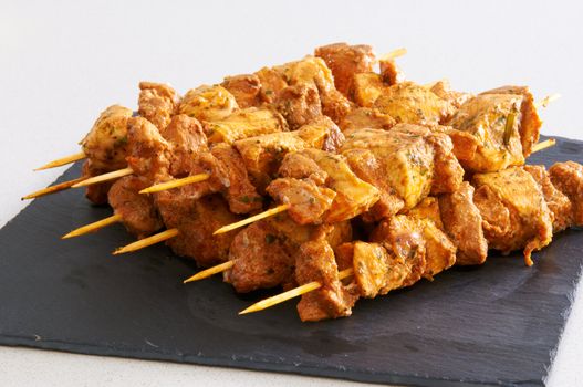 Meat brochettes on a black slate tray
