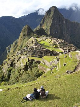 2 tourists looking at the mysterious city of Machu Picchu, Peru
