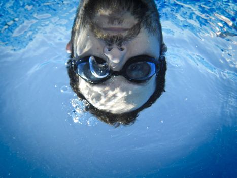 Man face swimming underwater in the pool