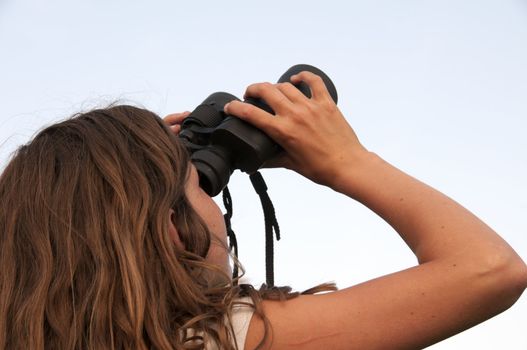 young girl with binoculars looking at the sky