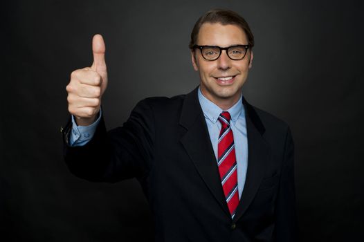 Businessman showing thumbs up sign to his team. Awesome performance by his team