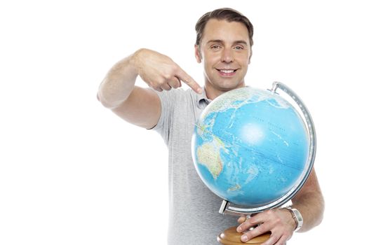Man holding globe and pointing over it against white background