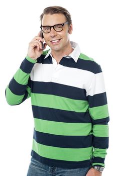 Smiling casual young person talking over cellphone to his friend