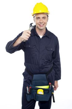 Smiling repairman holding out screwdriver from among his tool kit