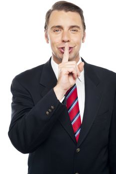 Smiling young smart business representative gesturing silence