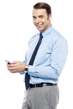 Smiling young manger sending sms from phone to his business colleagues