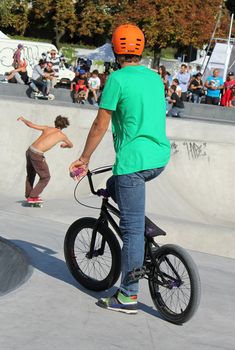 GENEVA, SWITZERLAND - SEPTEMBER 4 : young BMX biker looking at a man skating at the brand new skate park at Plainpalas place, on September 4, 2012 in Geneva, Switzerland.