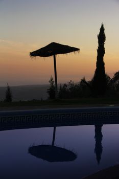 Tranquil scene with straw umbrella and nice sunset