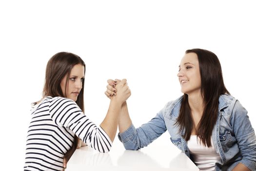 one happy and one strained teenager arm wrestling on white background