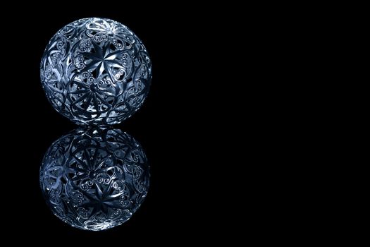 blue metal christmas ball on a black mirror on black background