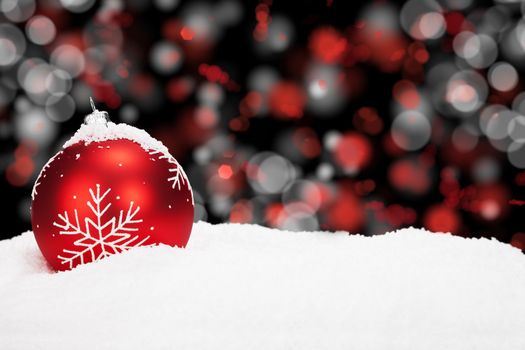 red christmas ball in snow with abstract background lights