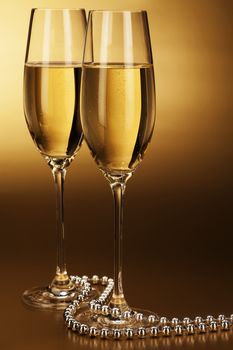 two glasses of champagne with a silver chain on golden background