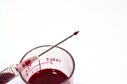 Needle of syringe with blood drop. Isolated over white