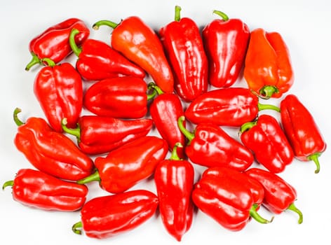 Many red sweet peppers lay on white background