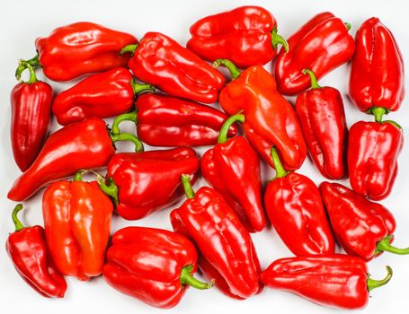 Many red sweet peppers lay on white background