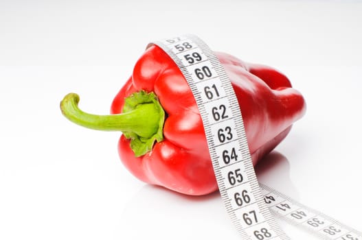 Red sweet pepper in measure tape isolated on white background