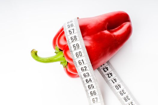 Red sweet pepper in measure tape isolated on white background