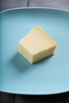 still life of piece of cheese on blue plate