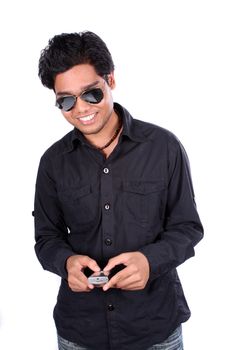 A young Indian guy smiling when sending a sms on his phone, on white studio background.
