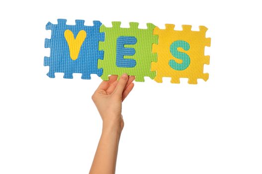 teacher holding in the hand the amusing colored educational puzzles with the word yes