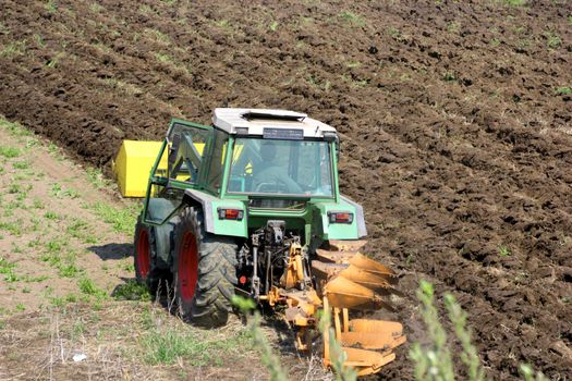 green tractor ploughing the land in spring