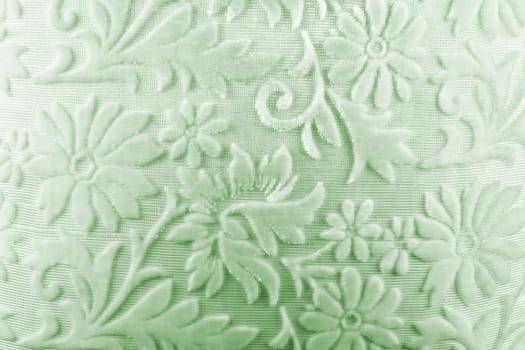 A background of a soft light green colored fabric with floral pattern.