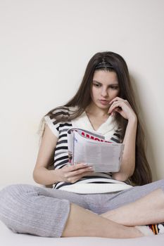 Young woman in bed rearding a fashion magazine