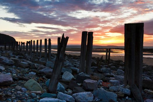 Old sea defences on the beach in Conwy at sunset