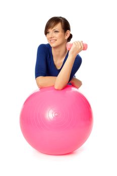 Instructor taking exercise class using ball and dumbbells at gym