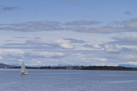 coastline with singel sailing boat in norway. cloudy sky